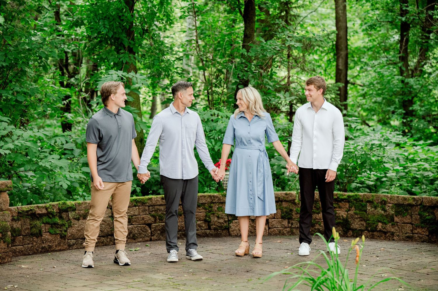 Family members stroll along stone walkway surrounded by vibrant green forest scenery.
