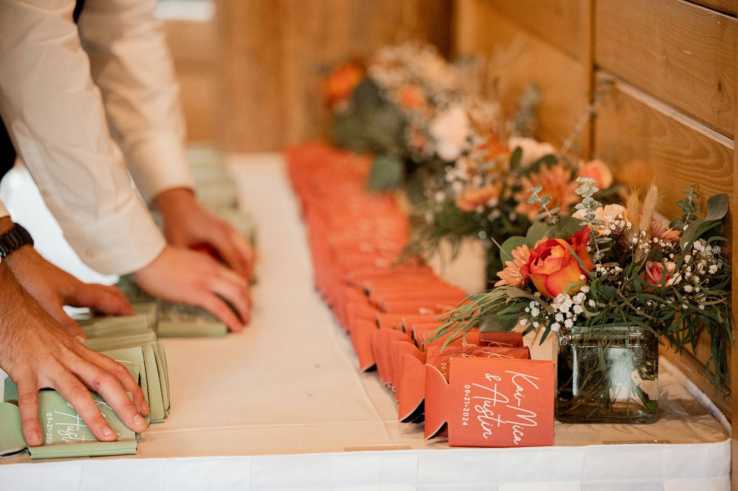The Grands at Mulligans- Wedding Photos: Close-up shots of coral table settings with hands arranging decorative greenery and place setting