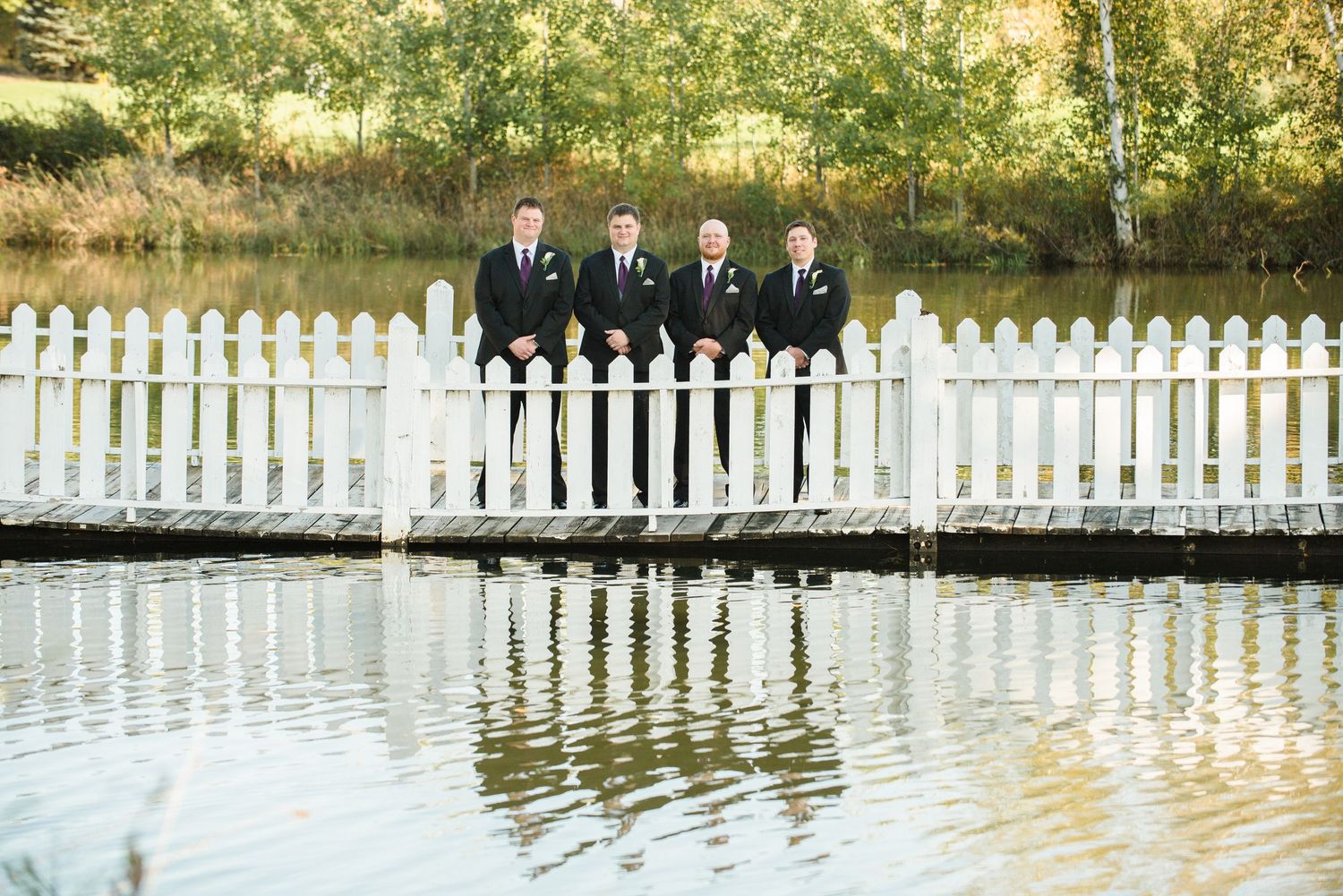 Long white picket fence stretches across a sunlit garden landscape. Andover wedding at Magestic Oaks Golf Club