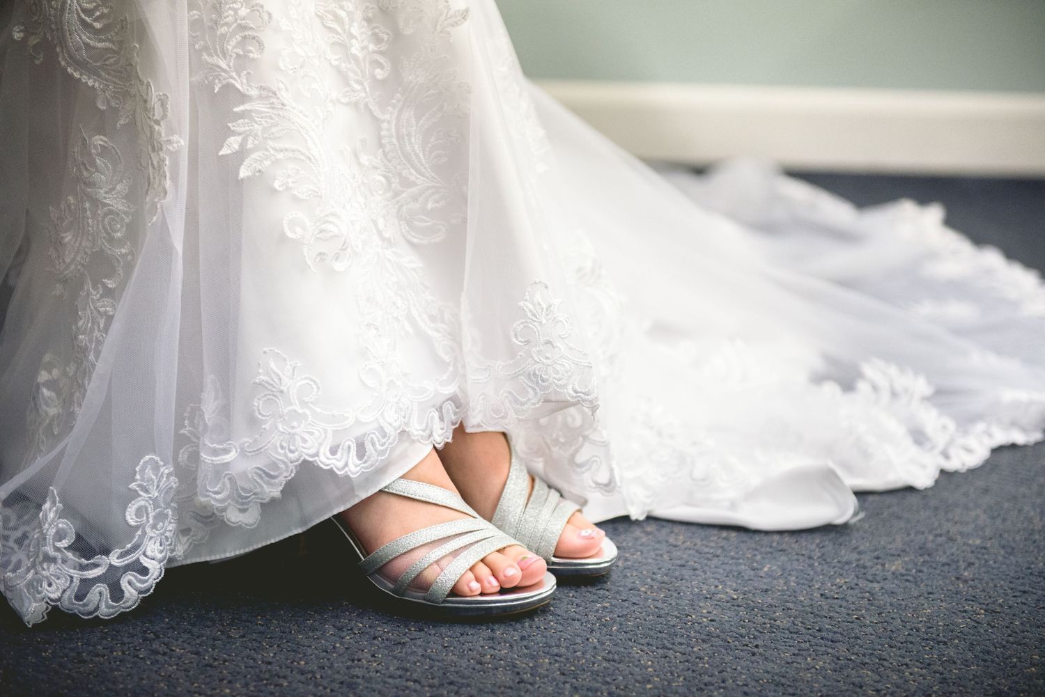 Silver strappy bridal sandals peeping beneath the hem of a lace wedding dress. Andover wedding at Magestic Oaks Golf Club