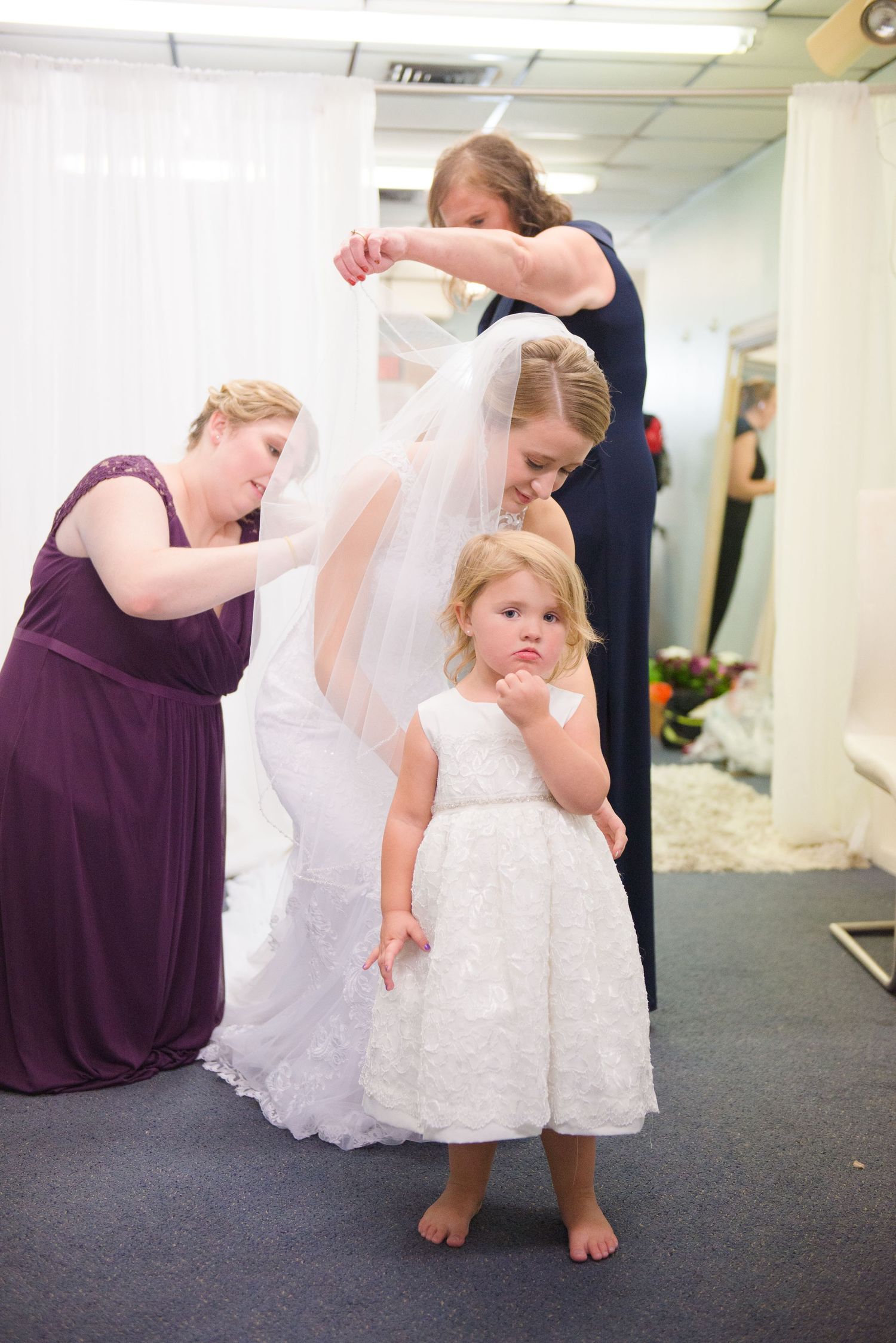 Wedding preparation scene with people in purple and white dresses making final adjustments. Andover wedding at Magestic Oaks Golf Club