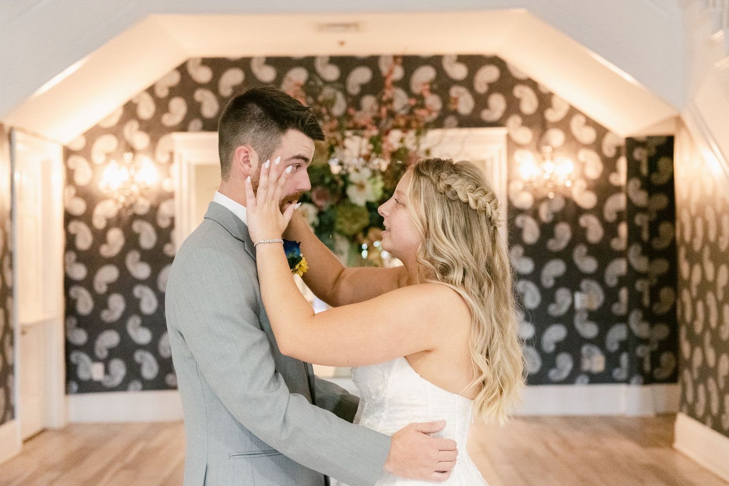 An intimate moment shared between a couple during their first look in a beautifully lit venue.
