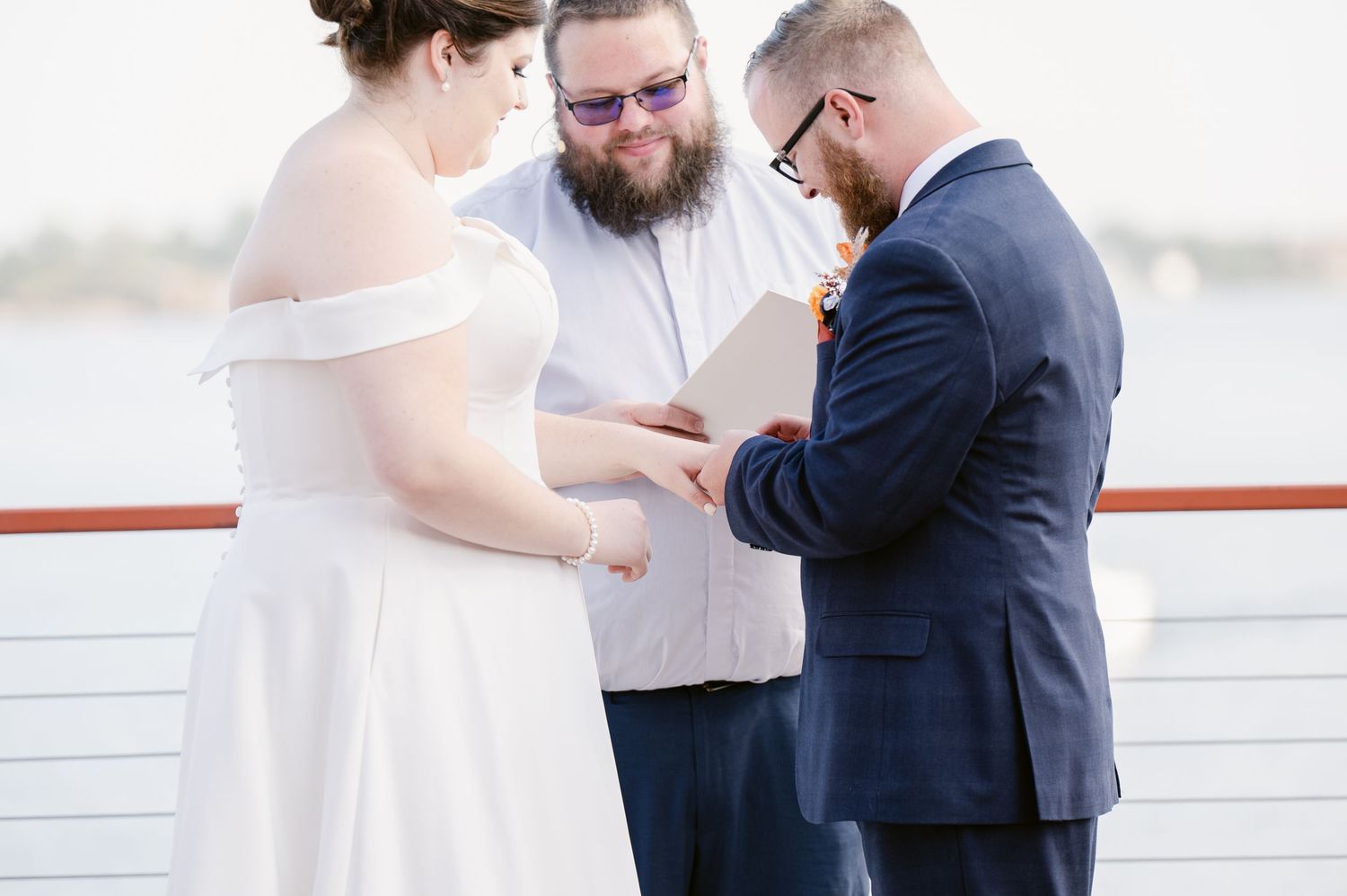 Pier B Duluth Wedding Wedding ceremony on waterfront deck with couple in white dress and navy suit.