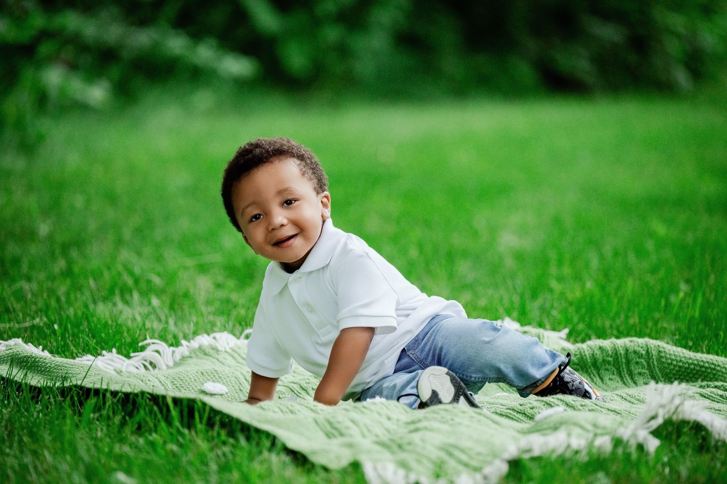 Child relaxing on blanket in grass during outdoor photoshoot.