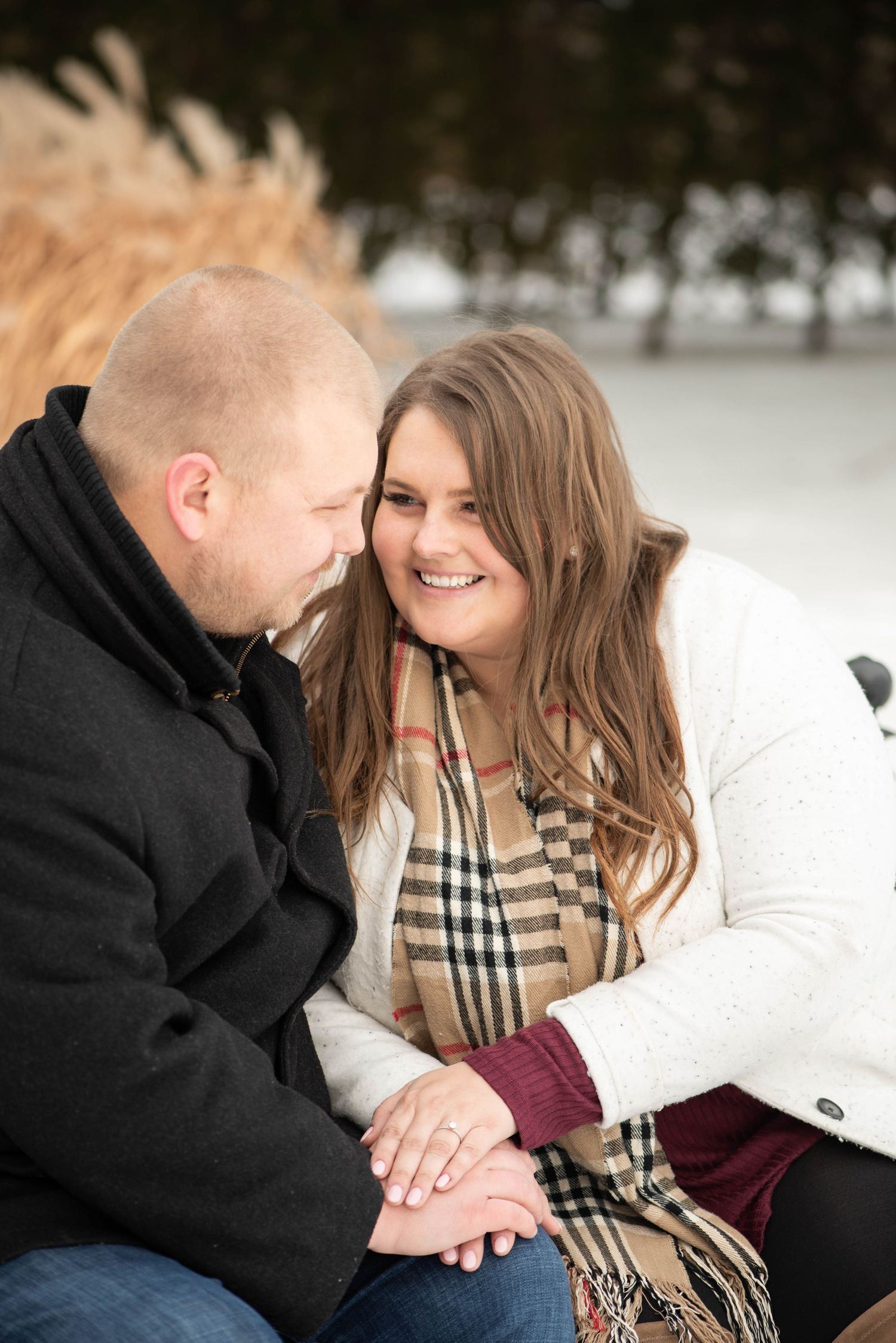 A romantic couple shares intimate moments in a snowy winter setting while wearing cozy scarves and outerwear.