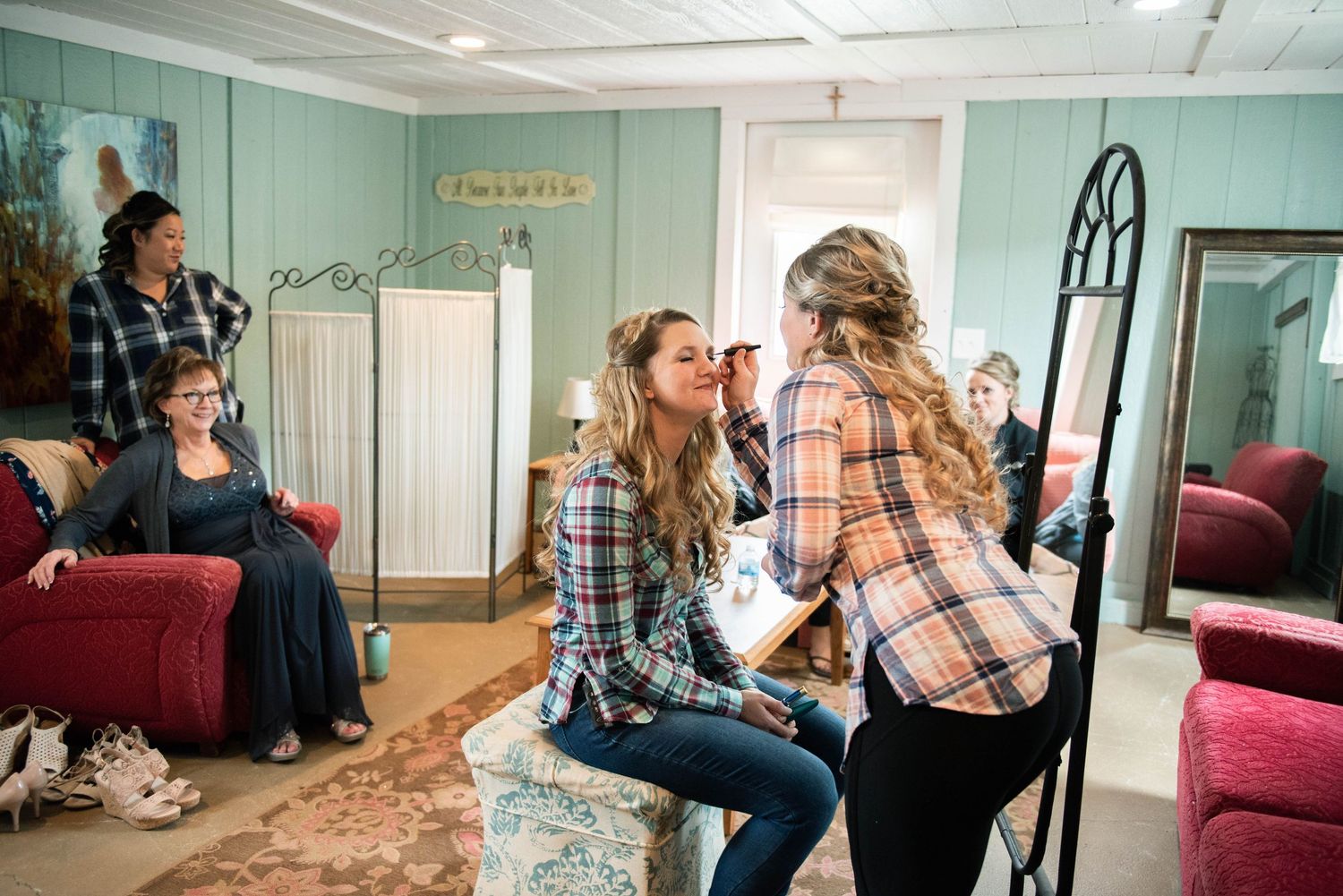 A bridal preparation scene in a mint green room with people gathered around.