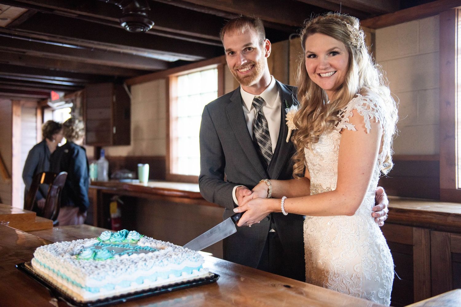 A couple in wedding attire cuts their wedding cake together at their reception. Rum River Barn Milaca Minnesota Weddings