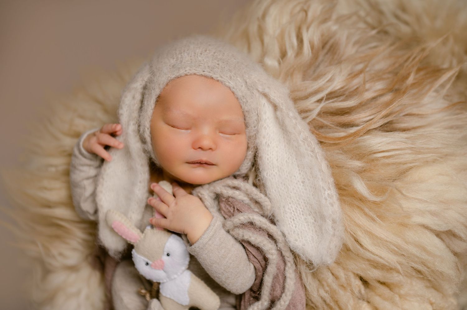 Six dreamy cream-toned newborn photography shots show a baby nestled in soft fluffy blankets and textures.