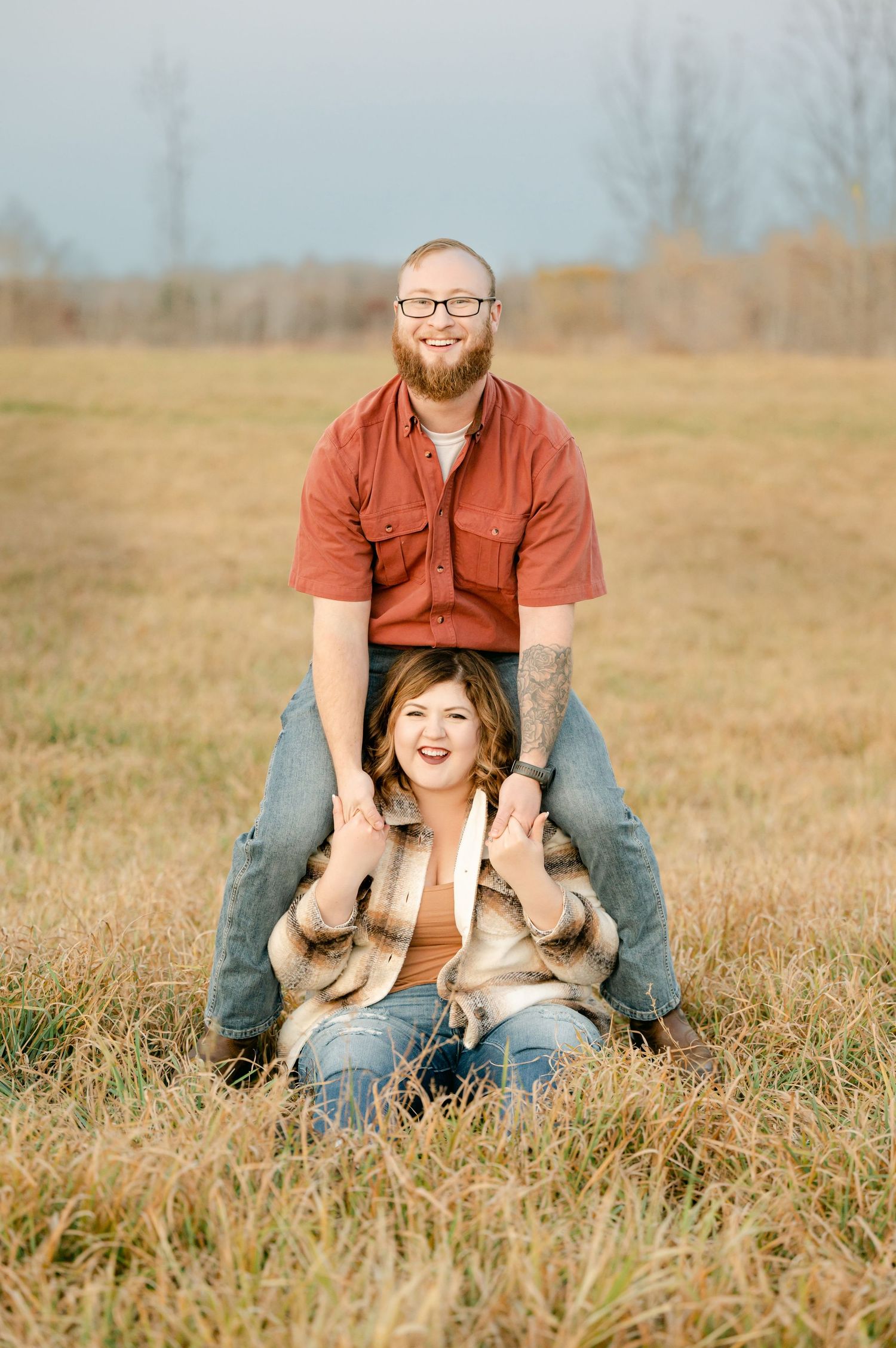Playful outdoor photoshoot in a golden field showing joyful interaction between people on a sunny autumn day.