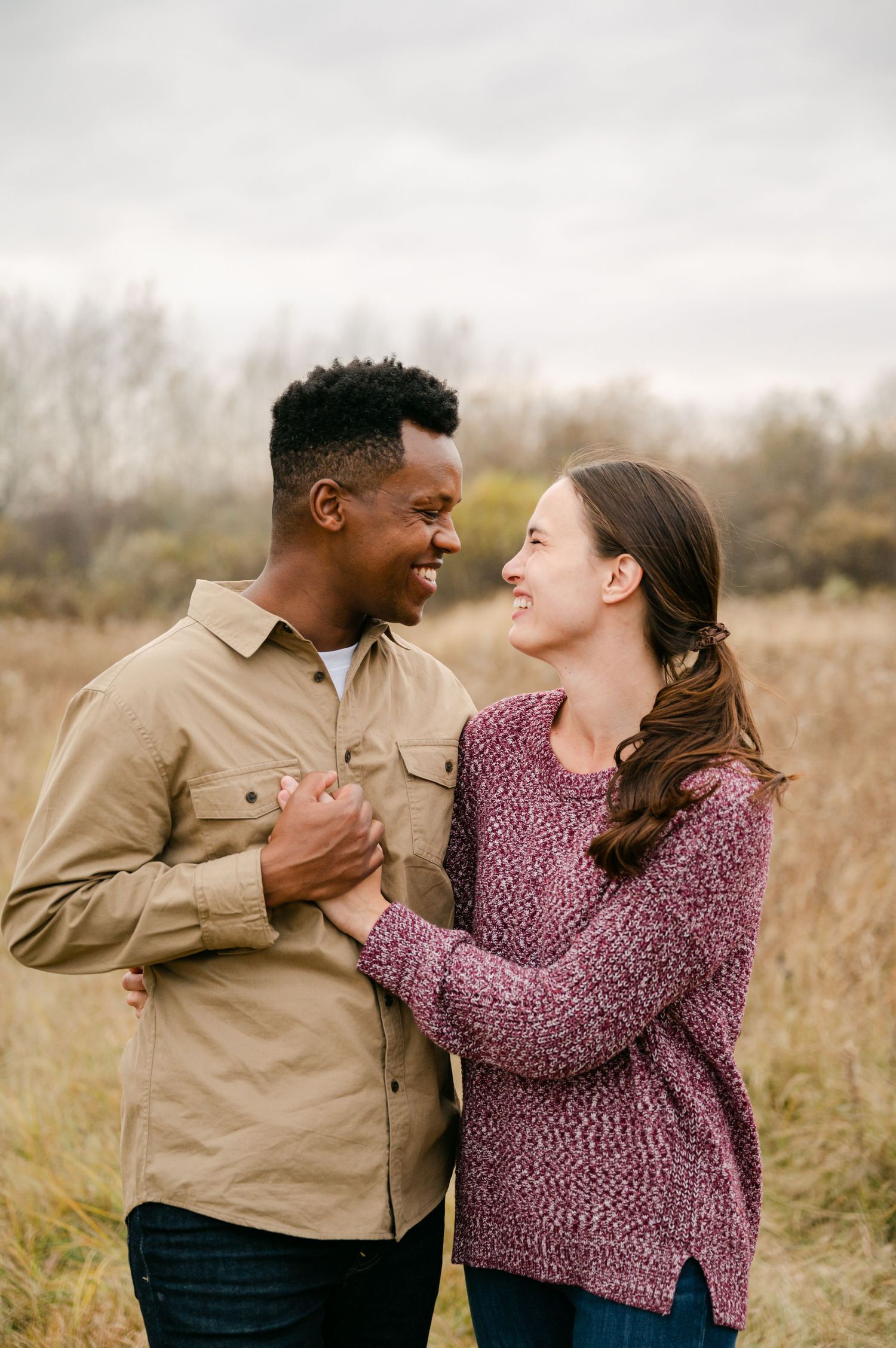 Two people share a romantic moment laughing together in a field of tall grass during an outdoor photo session. Princeton MN Milestone, Mater