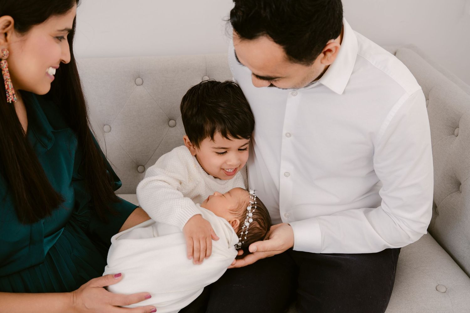 Family sits together on gray couch during intimate indoor photo session.