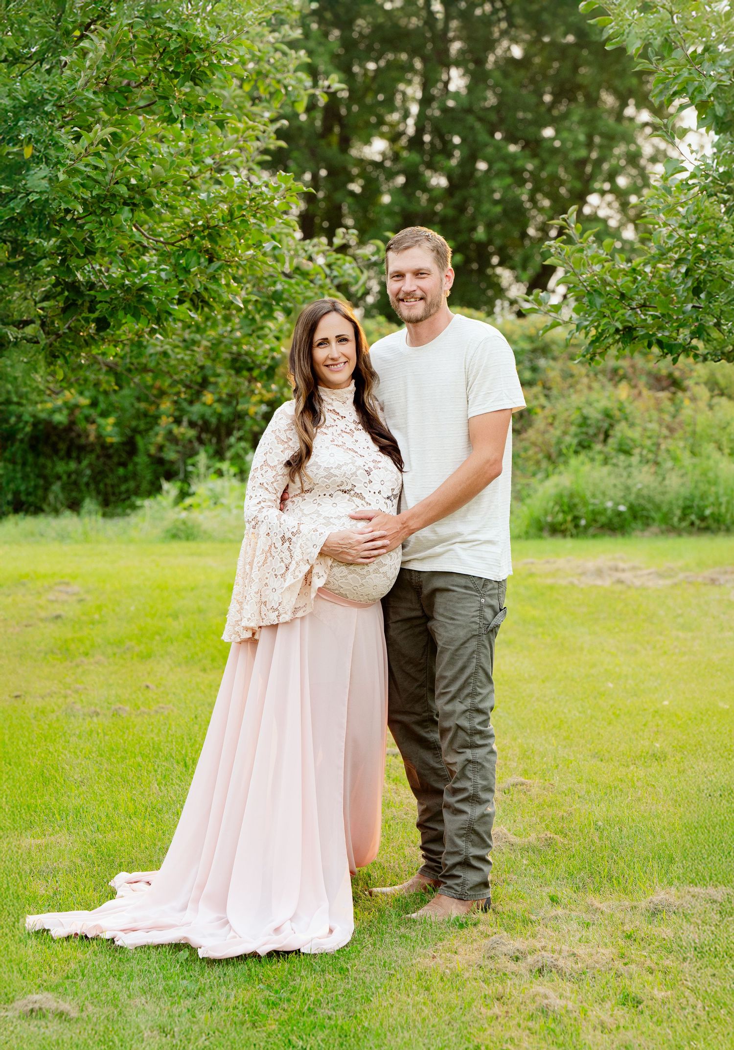 Couple poses together in garden during maternity photo session.