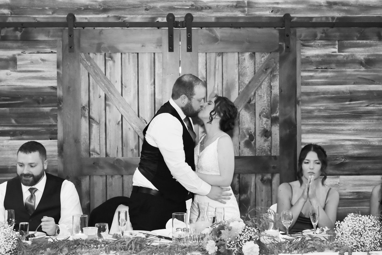 Black and white reception photos showing guests dining at rustic wooden tables.