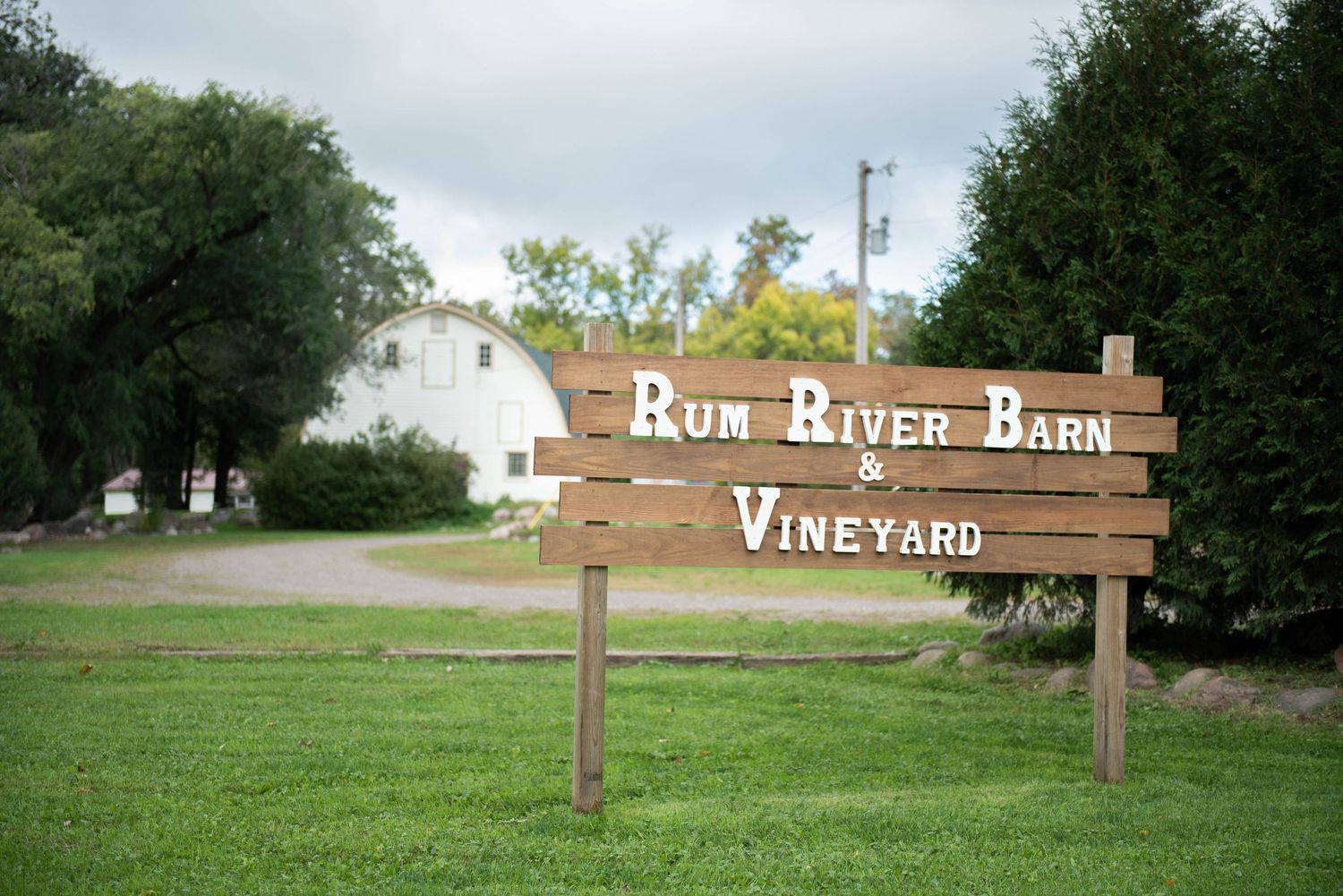 Rustic wooden signs point the way to a vineyard and barn venue in a rural outdoor setting. Milaca Minnesota Weddings