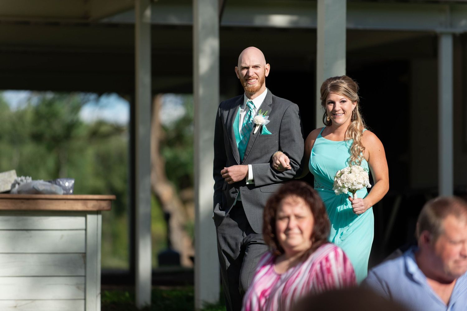 Wedding party members in turquoise and formal attire stand at an outdoor venue. Rum River Barn Milaca Minnesota Weddings