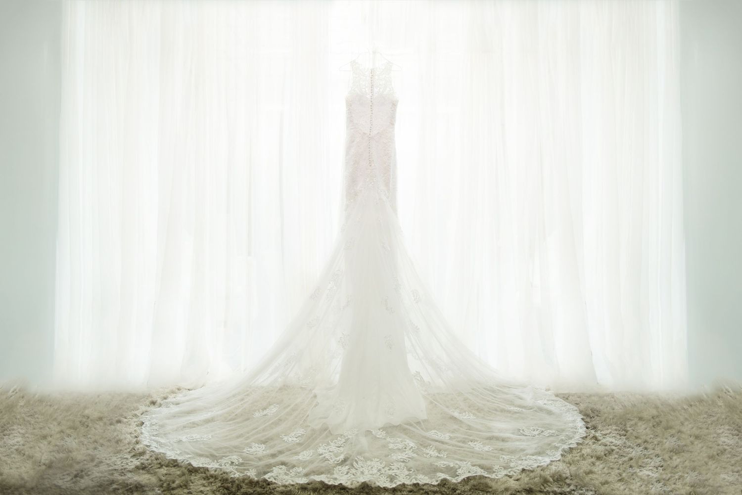 Flowing white wedding dress train with delicate lace details spread across a light colored floor. Andover wedding at Magestic Oaks Golf Club