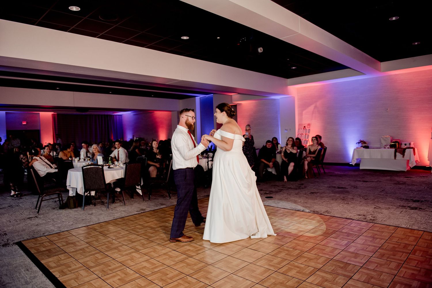 Pier B Duluth Wedding Wedding reception dance floor illuminated with colorful lighting as guests celebrate at an indoor venue.