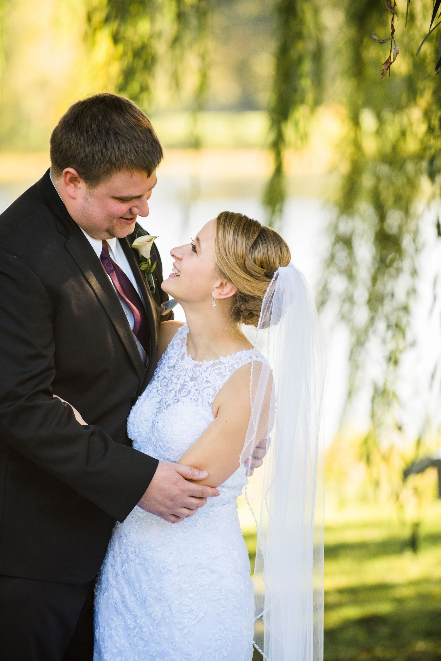 A romantic moment between newlyweds beneath golden willow trees during their wedding photoshoot. Andover wedding at Magestic Oaks Golf Club