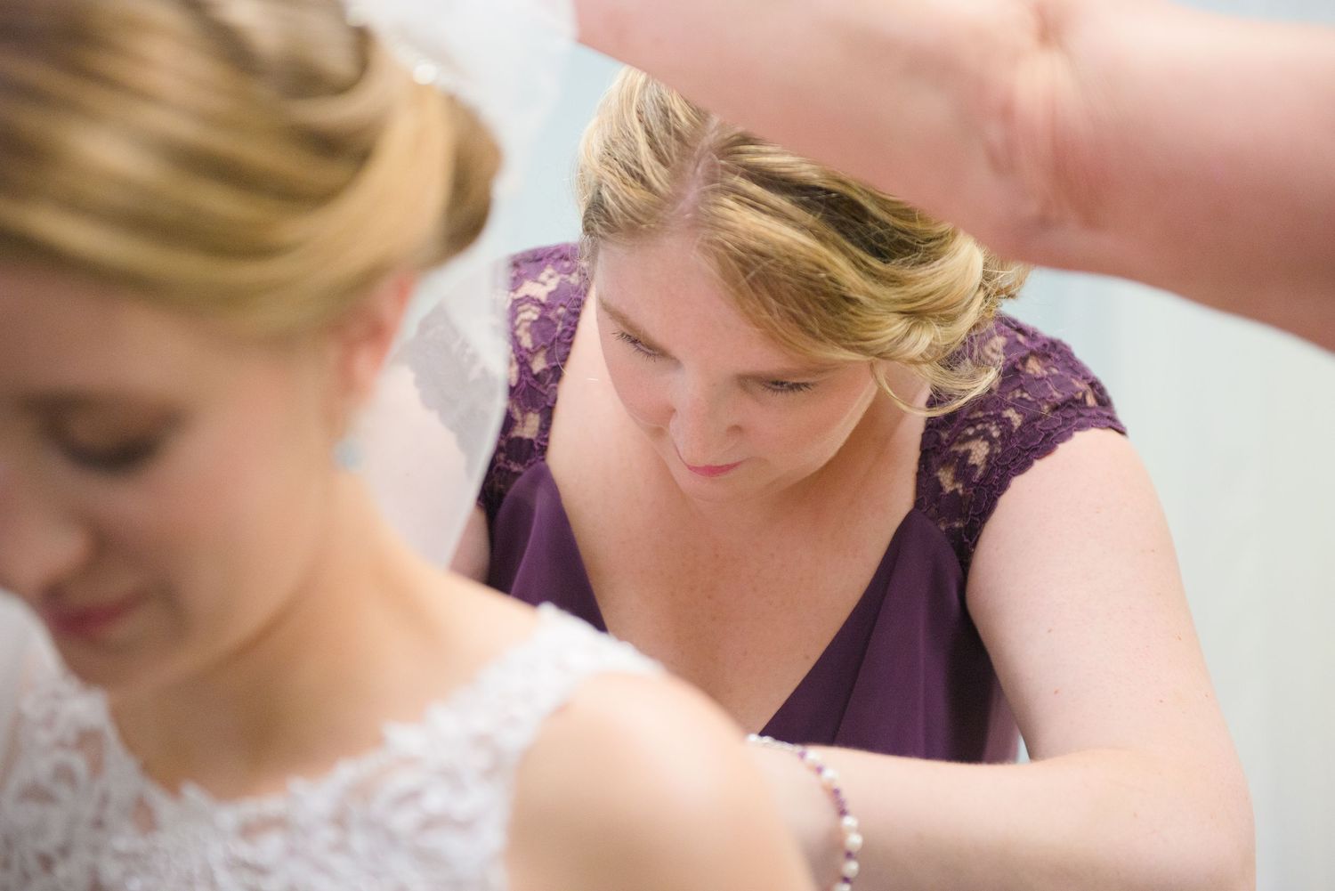 Close up view of a formal dress adjustment during a bridal preparation. Andover wedding at Magestic Oaks Golf Club