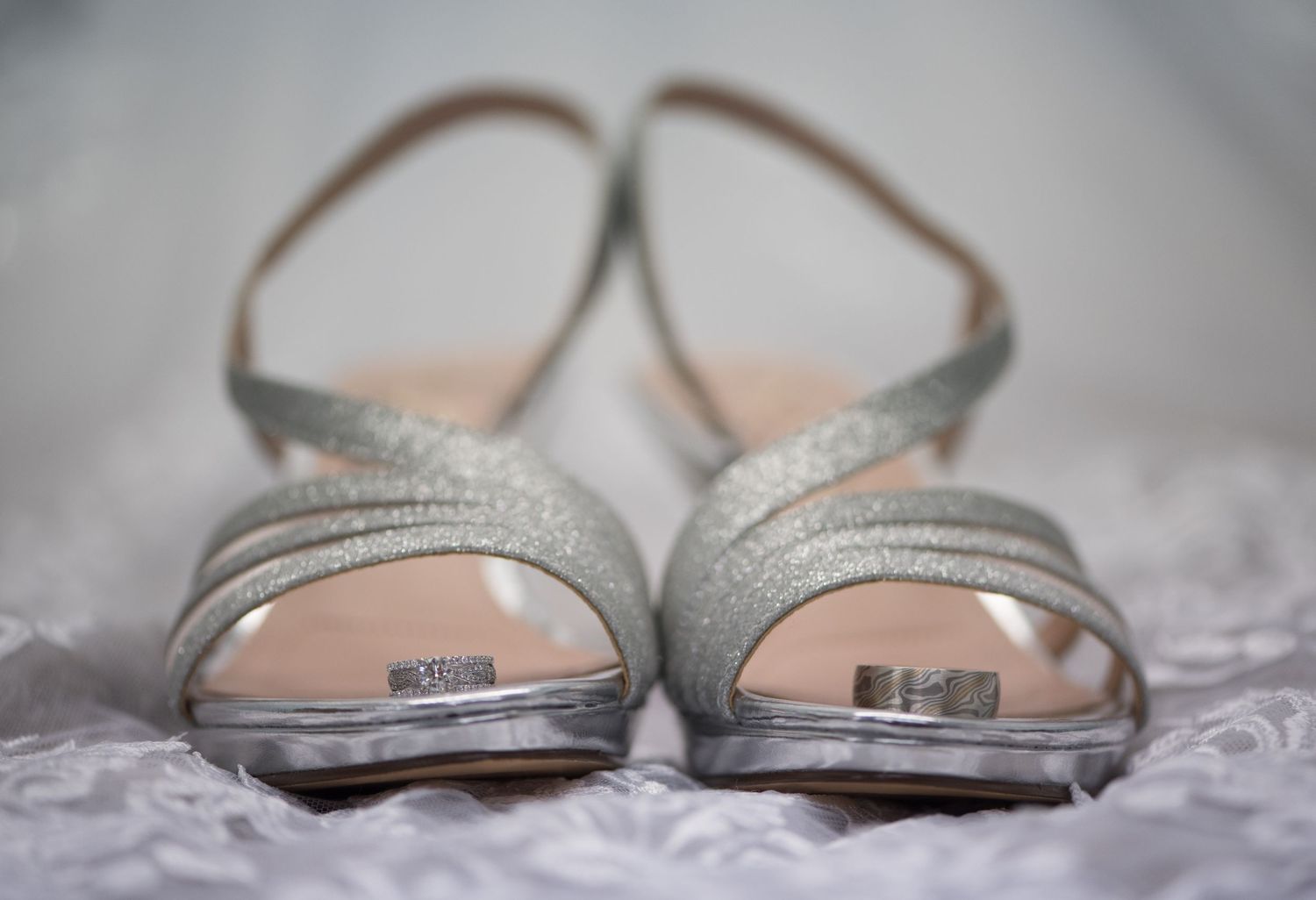 Silver glittery peep-toe bridal shoes with wedding rings placed on them. Andover wedding at Magestic Oaks Golf Club