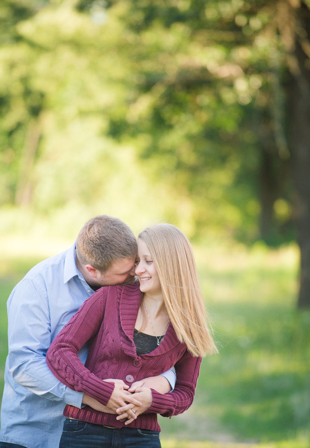 Intimate couple moment captured in a park setting with warm lighting and natural greenery.