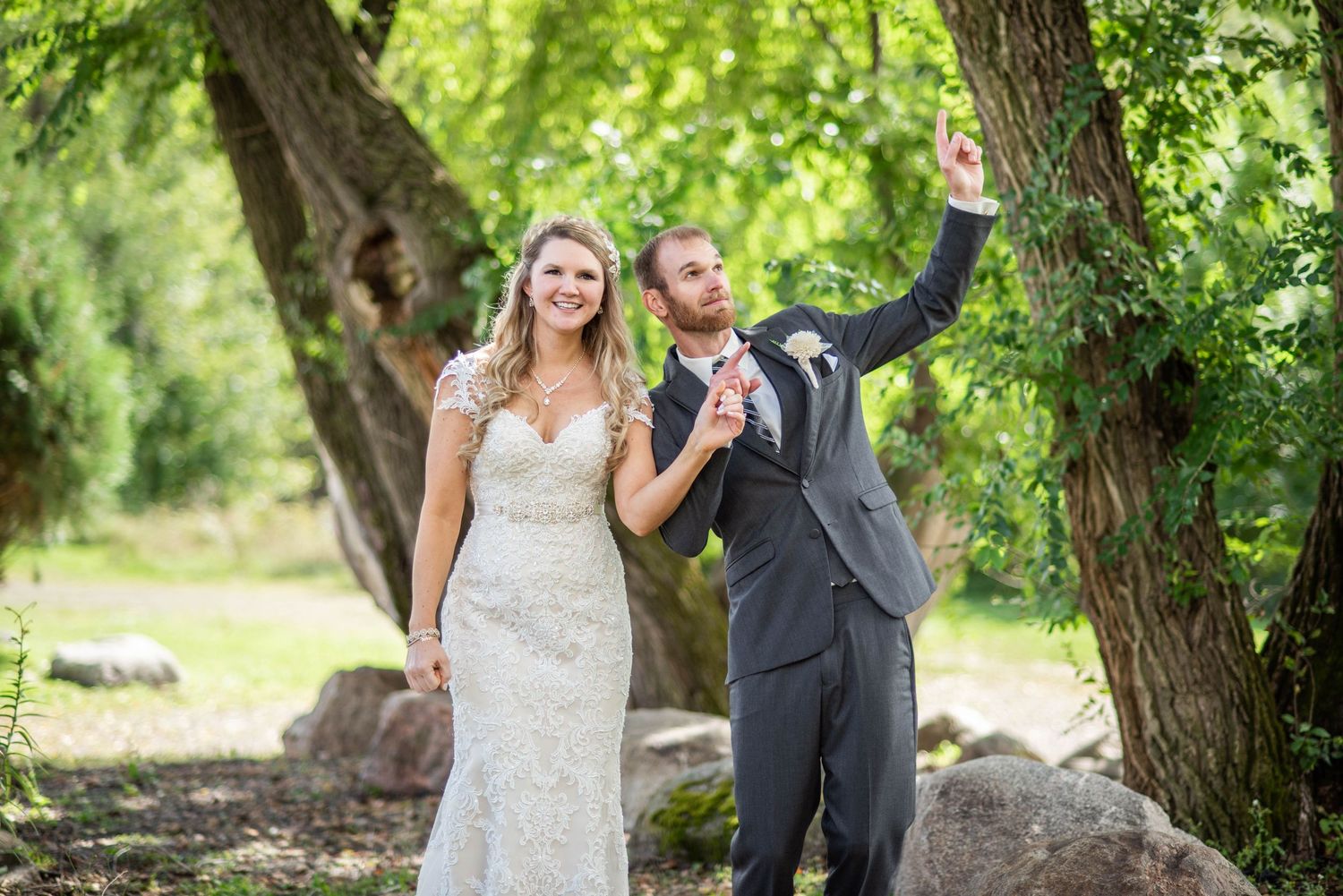 Newlyweds share a tender moment dancing amidst sunlit trees and fallen leaves.