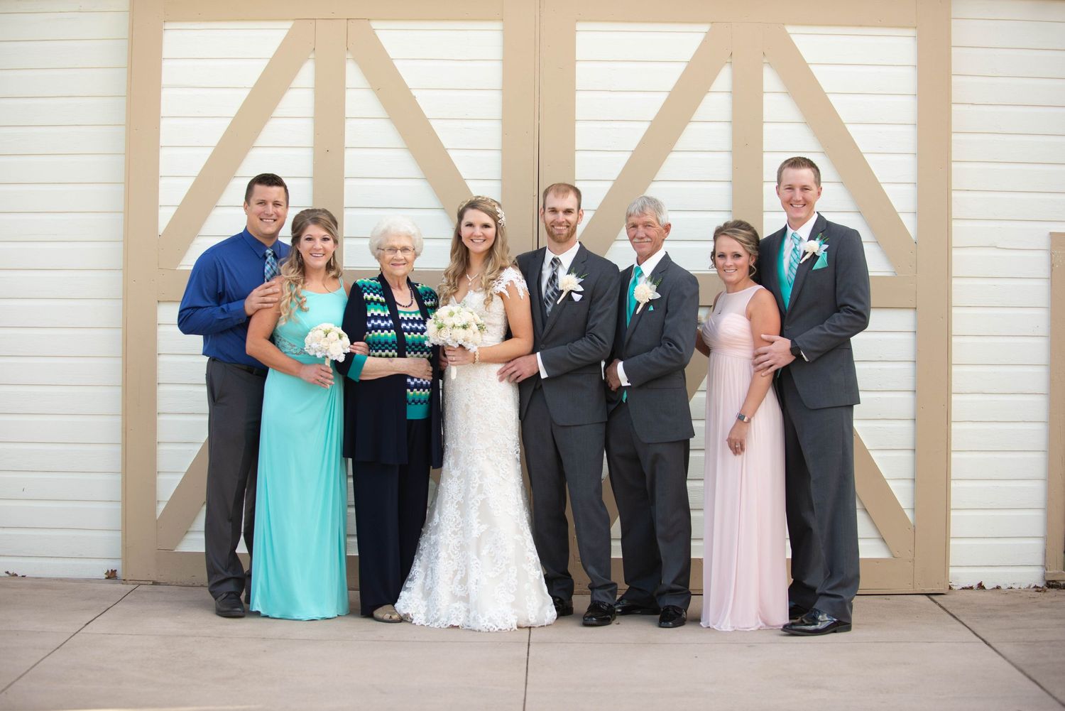 Wedding party poses in coordinated formal attire against a rustic barn door backdrop. Milaca Minnesota Weddings