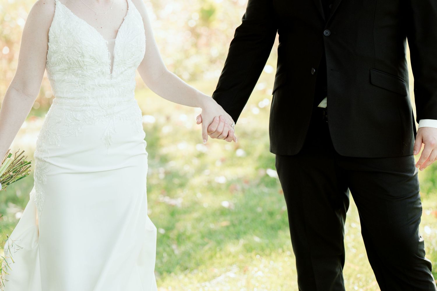 Bridal party arranged in a line wearing formal black suits and white dresses outdoors.
