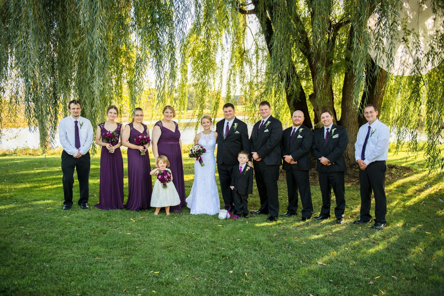 Wedding party lined up under weeping willow trees for outdoor formal photos. Andover wedding at Magestic Oaks Golf Club