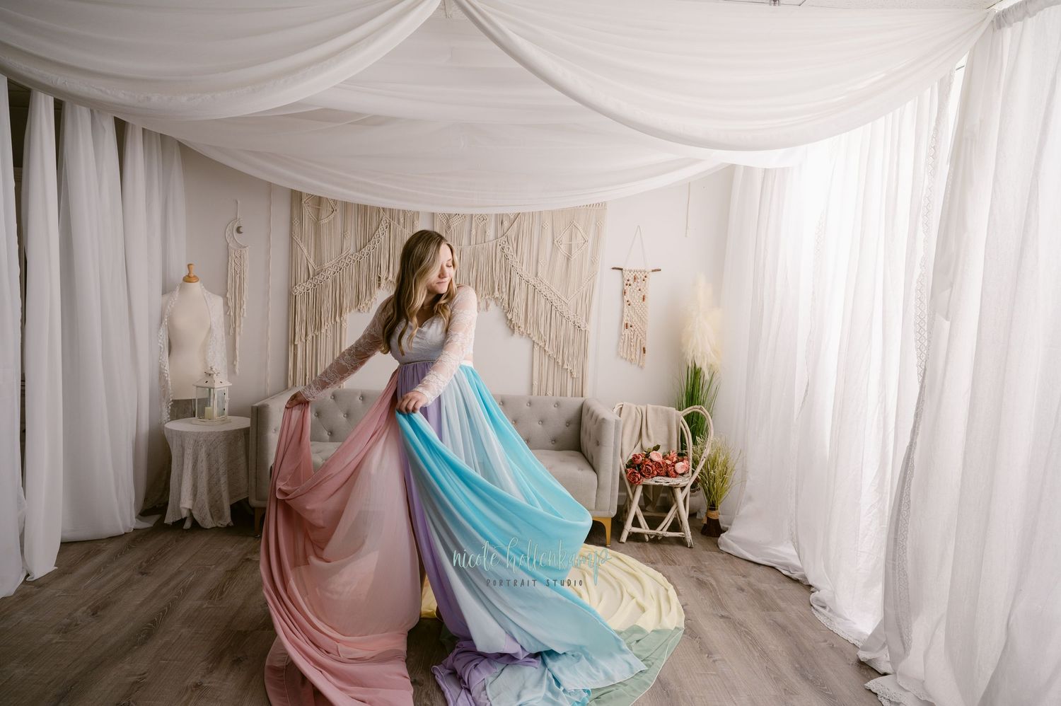 Flowing ombre gown in pink and blue tones twirls gracefully in a white draped studio setting with vintage decor.
