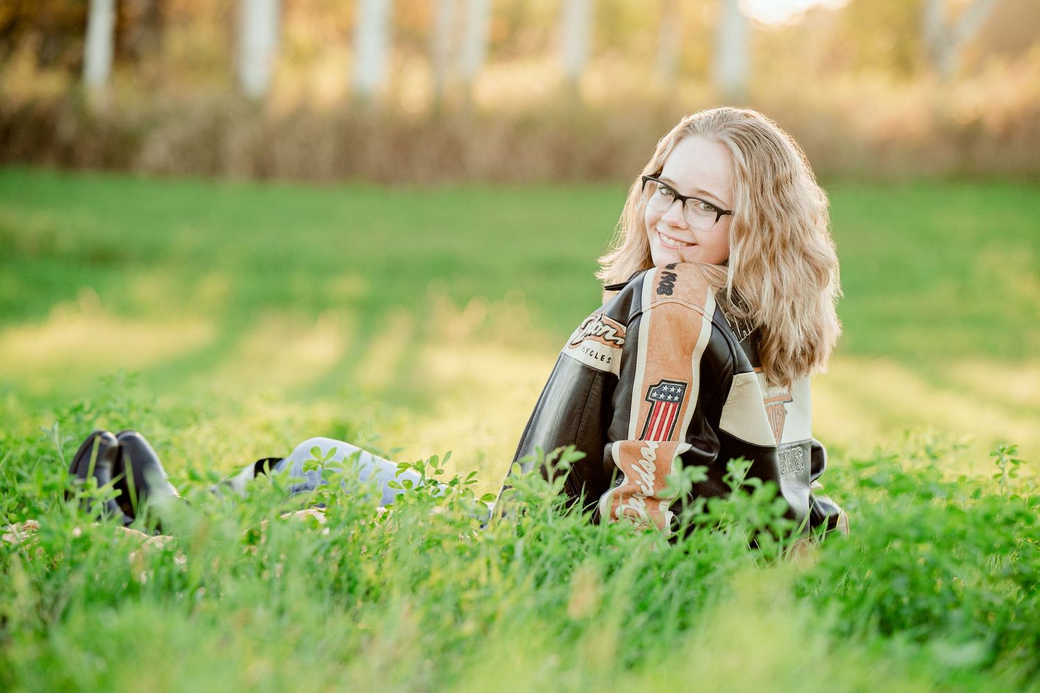 Senior Portrait in Foreston MN relaxes on grass with musical instrument during outdoor photo session.