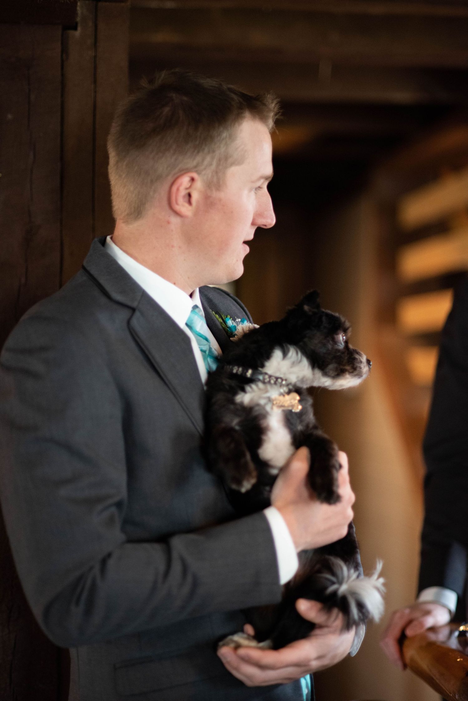 A person in a suit holds and pets a black and white cat during what appears to be a formal event.