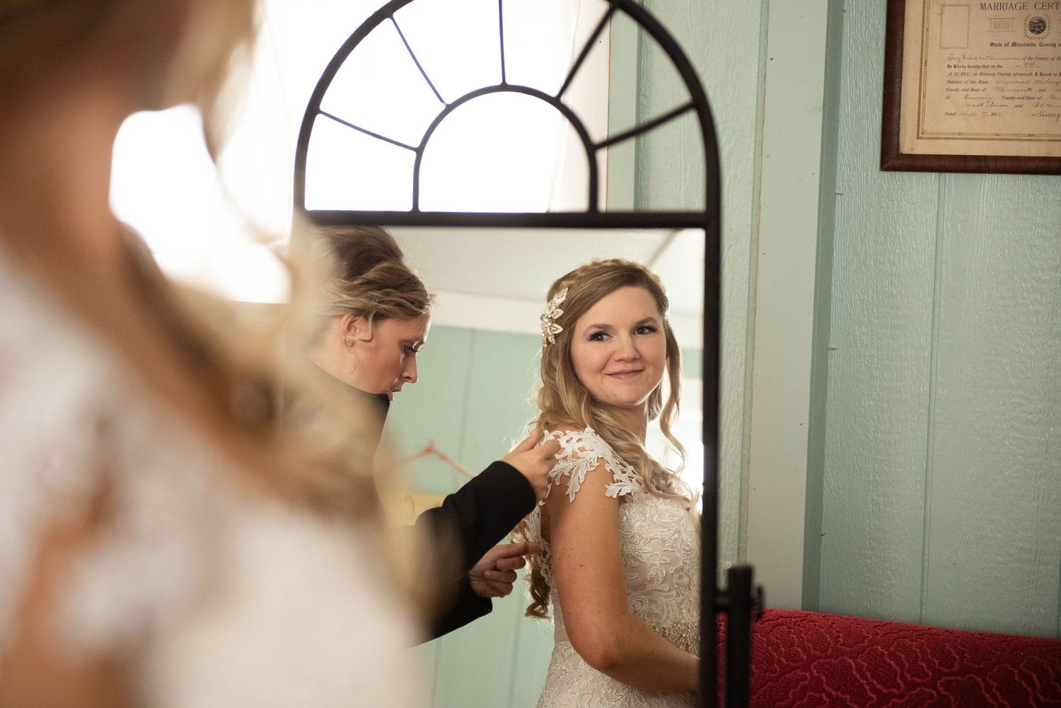Reflection of wedding preparations in an arched mirror against mint green walls.