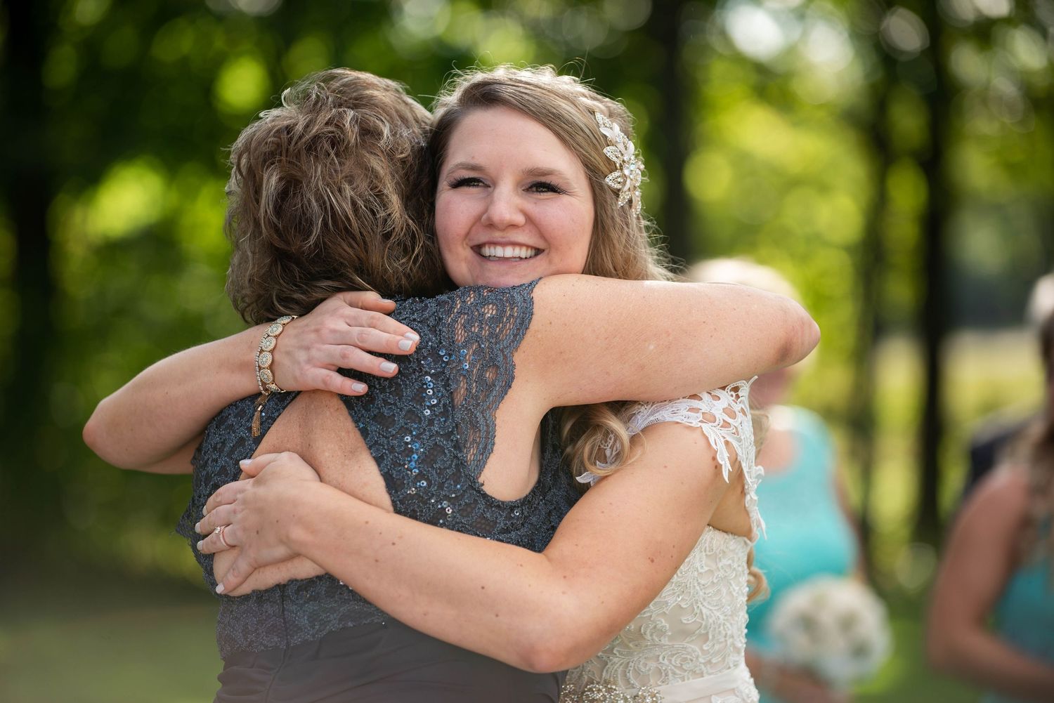 Wedding party members embrace during emotional moments at an outdoor venue. Rum River Barn Milaca Minnesota Weddings