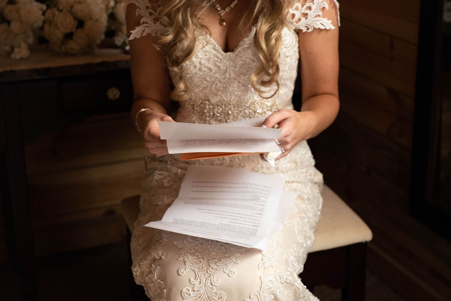 Close-up of hands holding papers while wearing an intricate lace wedding dress. Rum River Barn Milaca Minnesota Weddings