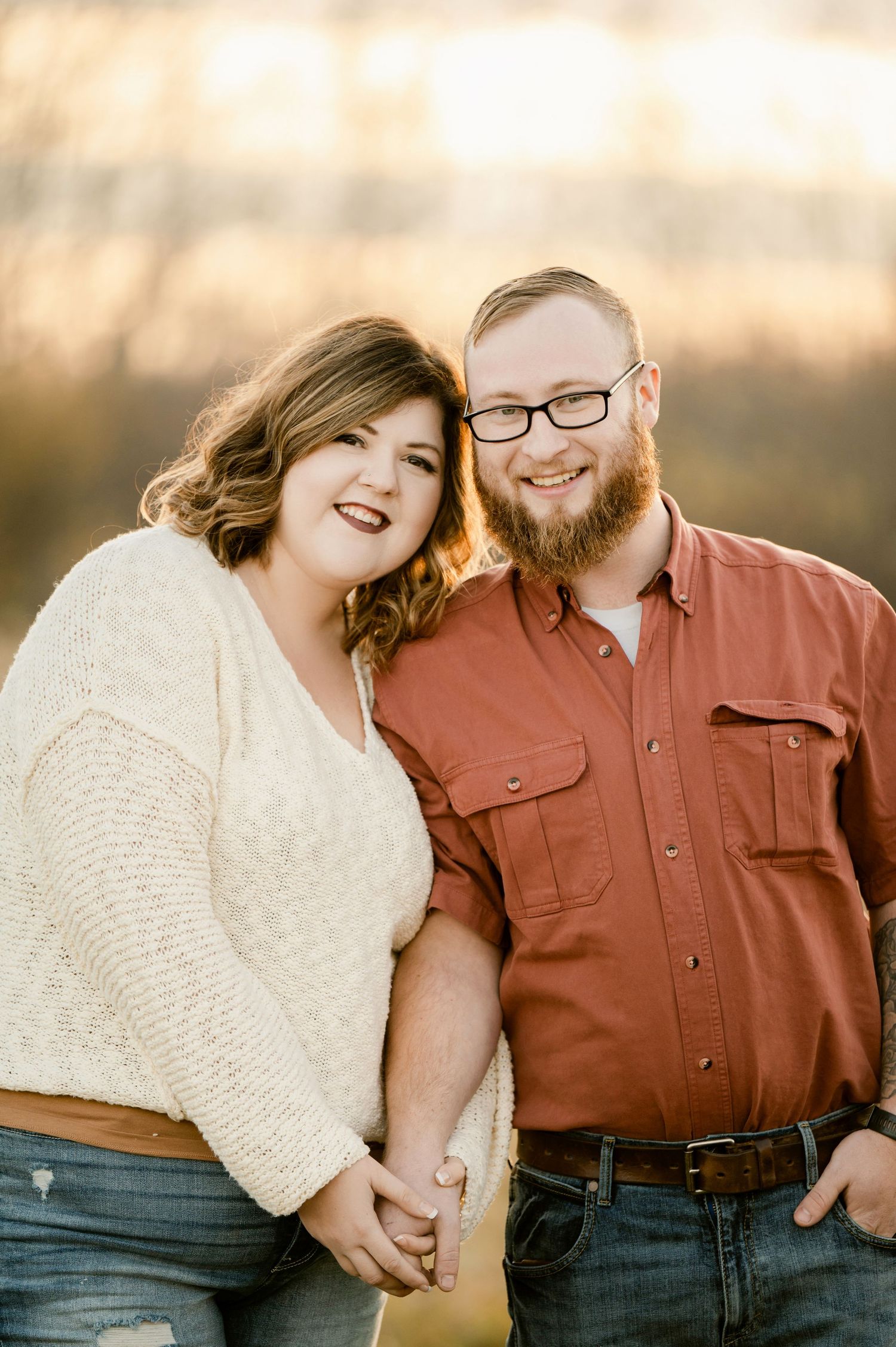 Happy couple share a joyful moment together in warm sunset lighting wearing casual attire. St cloud area engagement photos.