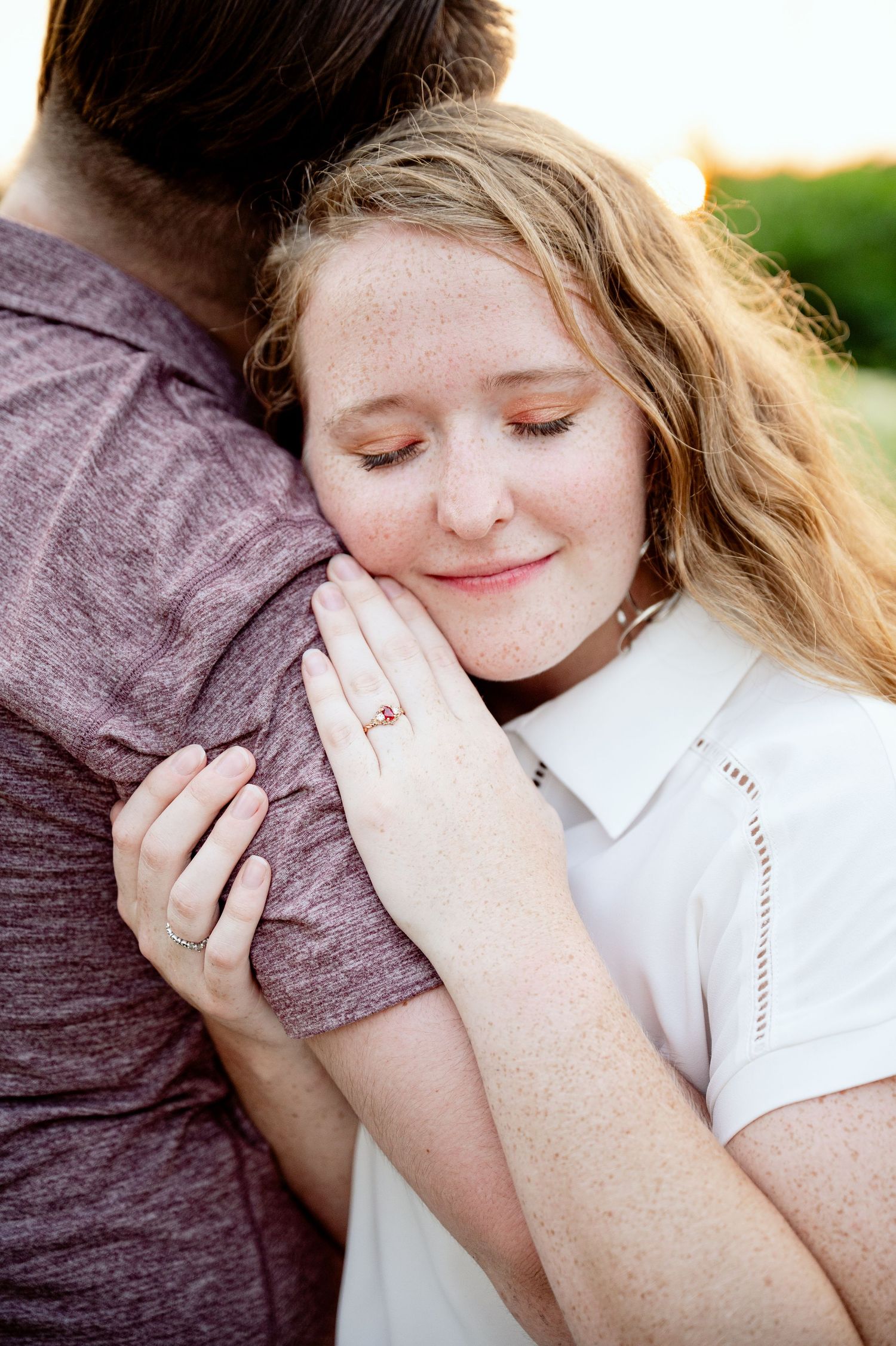 A tender embrace captured in natural lighting shows a romantic moment outdoors.