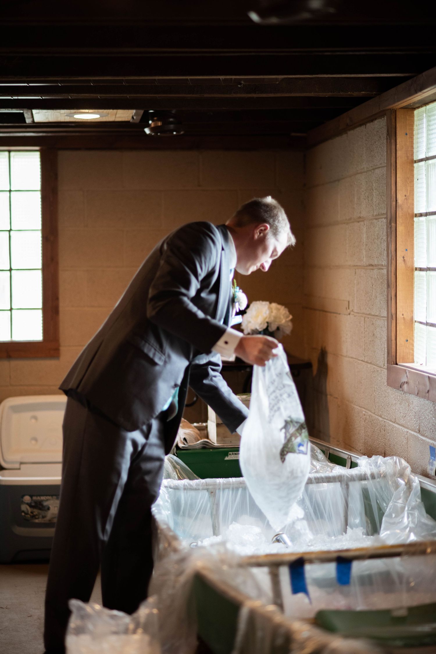 A person in a suit inspects a garment bag in a dimly lit basement storage area.