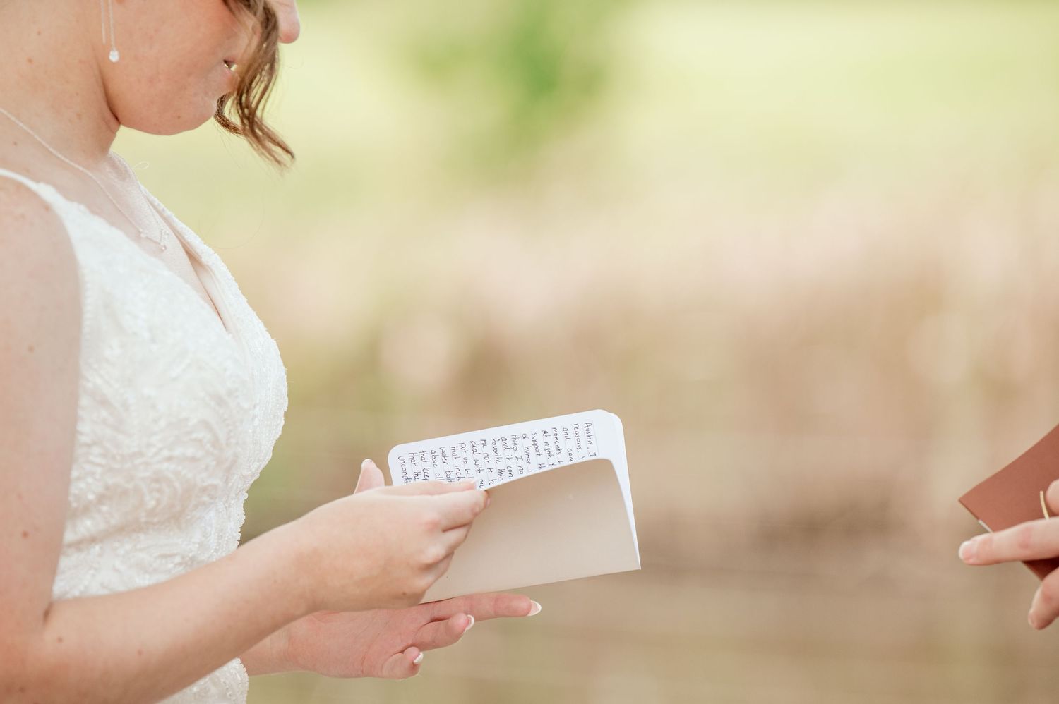 The Grands at Mulligans- Wedding Photos: Close-up of hands exchanging paper letters and cards at a wedding ceremony.