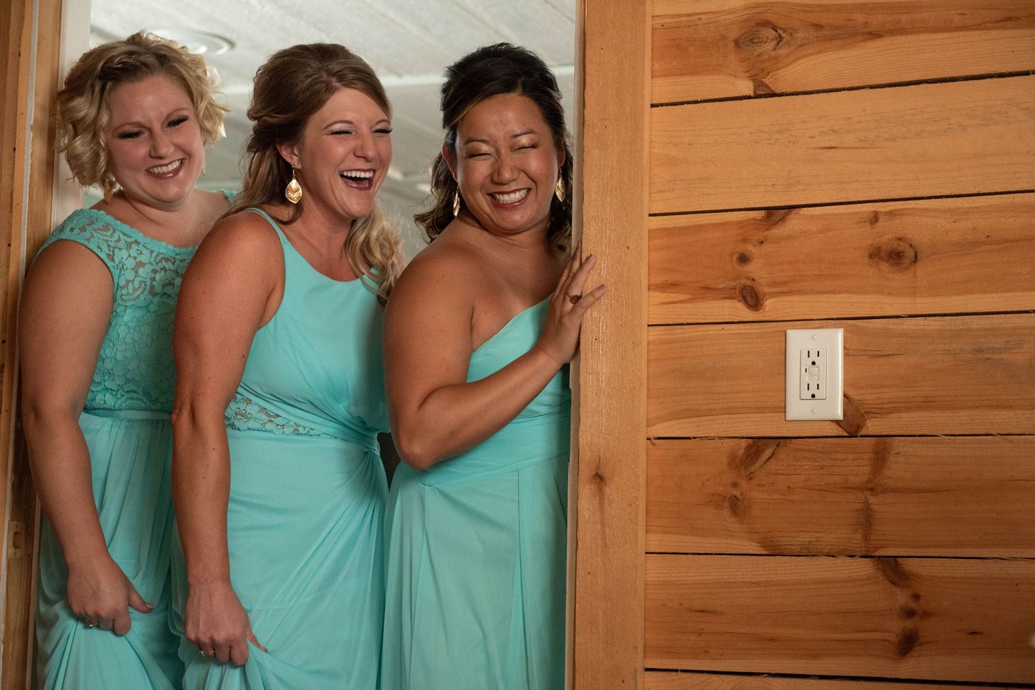 Group wearing matching turquoise dresses sharing joyful moments together. Rum River Barn Milaca Minnesota Weddings