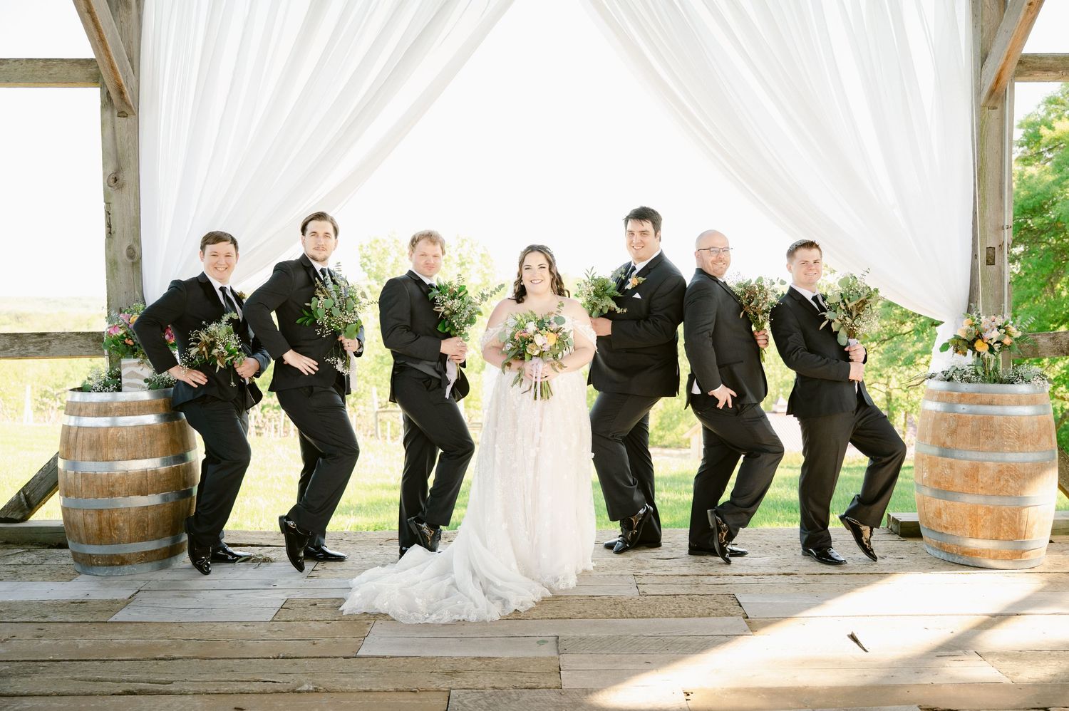 Groomsmen perform synchronized dance moves on rustic wooden platform.