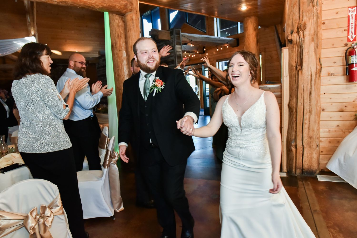 The Grands At Mulligans. Wedding reception celebration inside a rustic wooden barn venue with dancing guests.