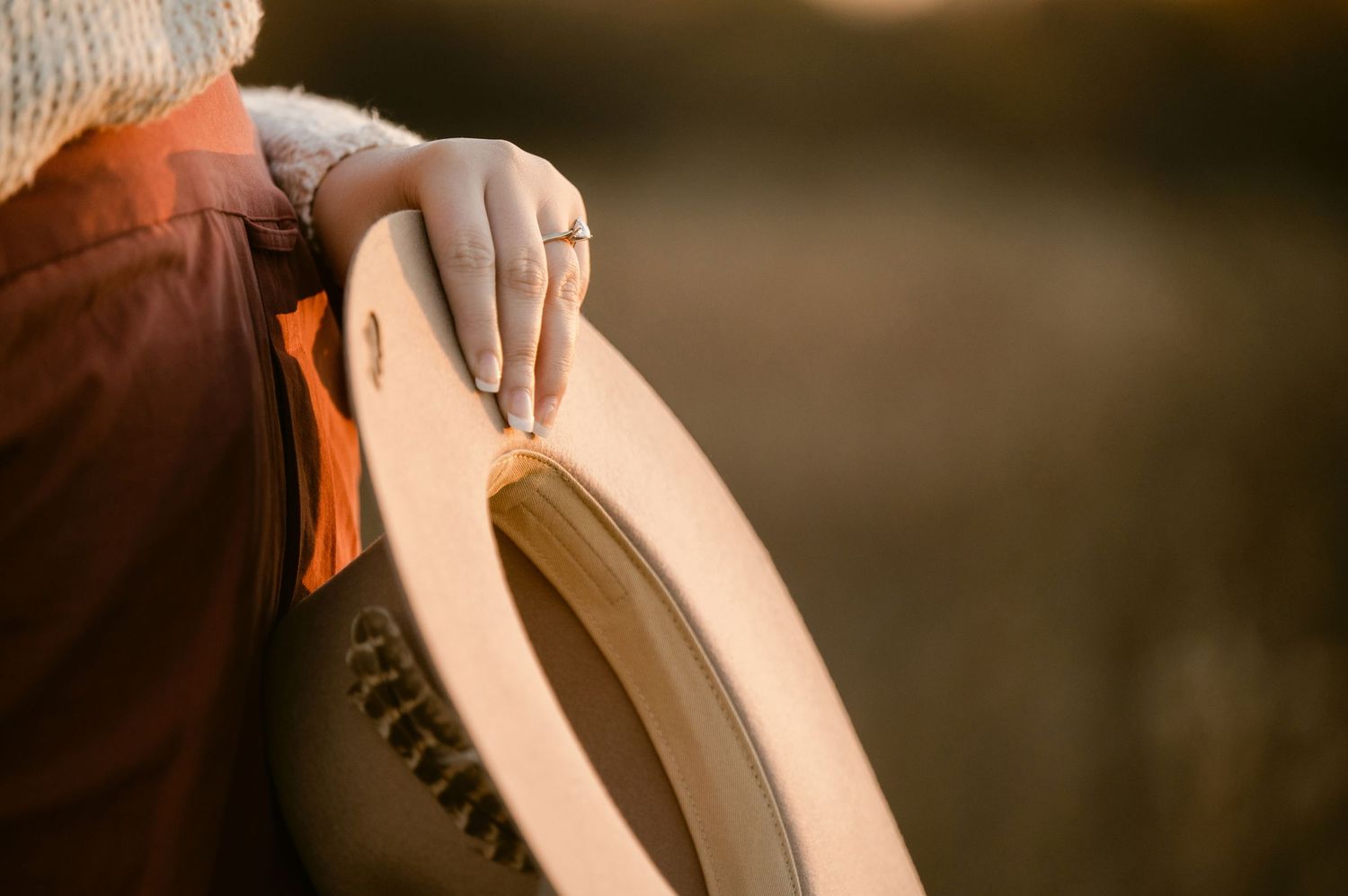 A hand wearing a leather glove holds the edge of a light tan leather workshop item in warm lighting. St cloud area engagement photos.