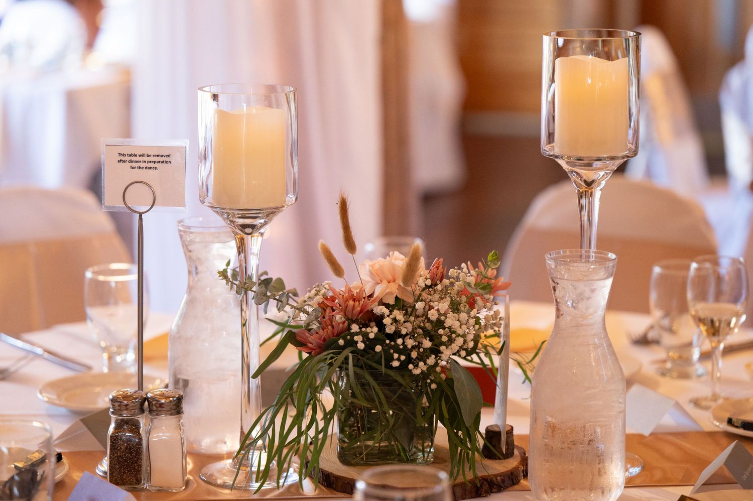 Elegant wedding reception table setting with glowing candles and floral centerpieces.