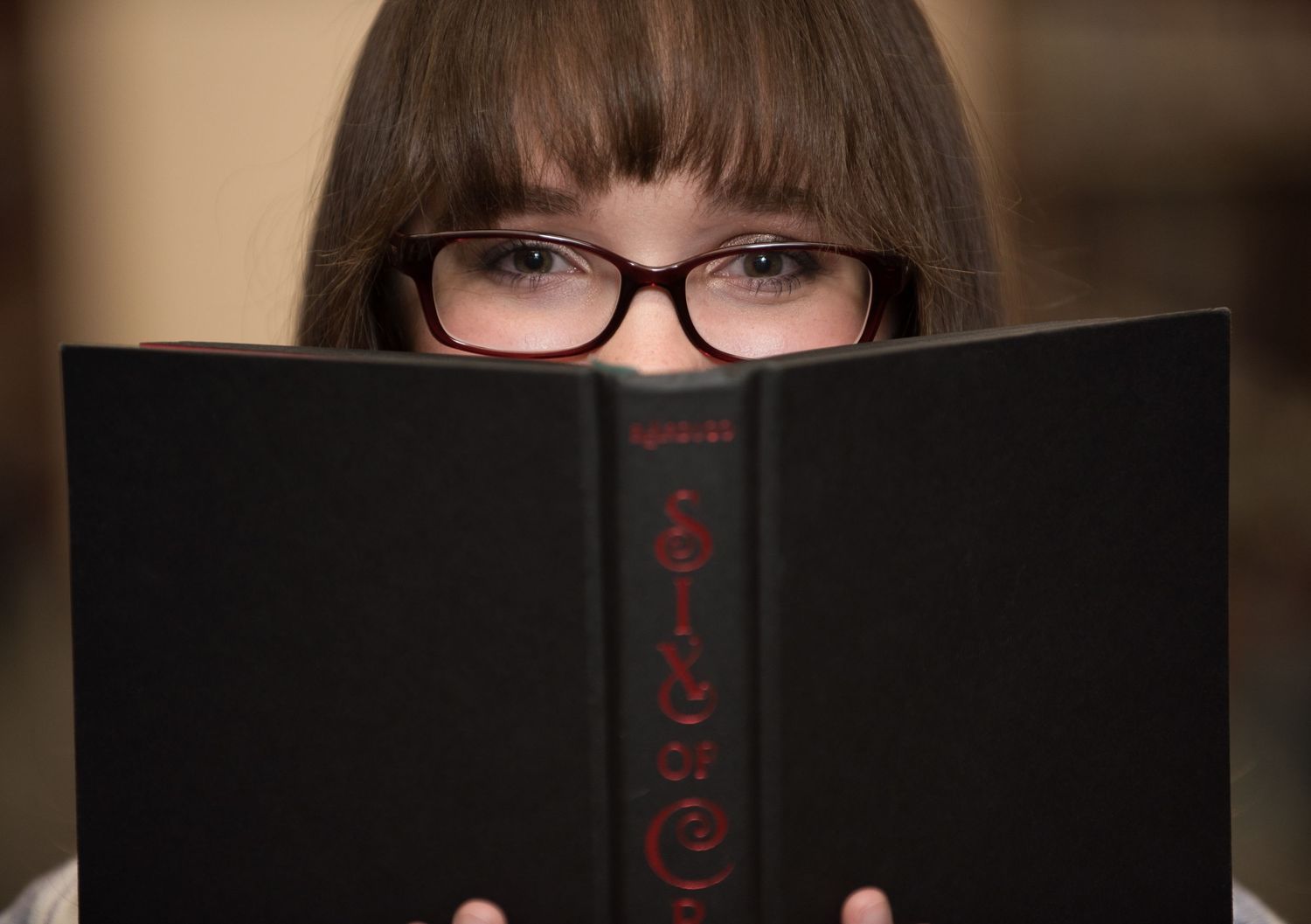Senior Portrait at St Cloud State College A book with red text covers most of a person's face, with only eyes visible behind glasses.