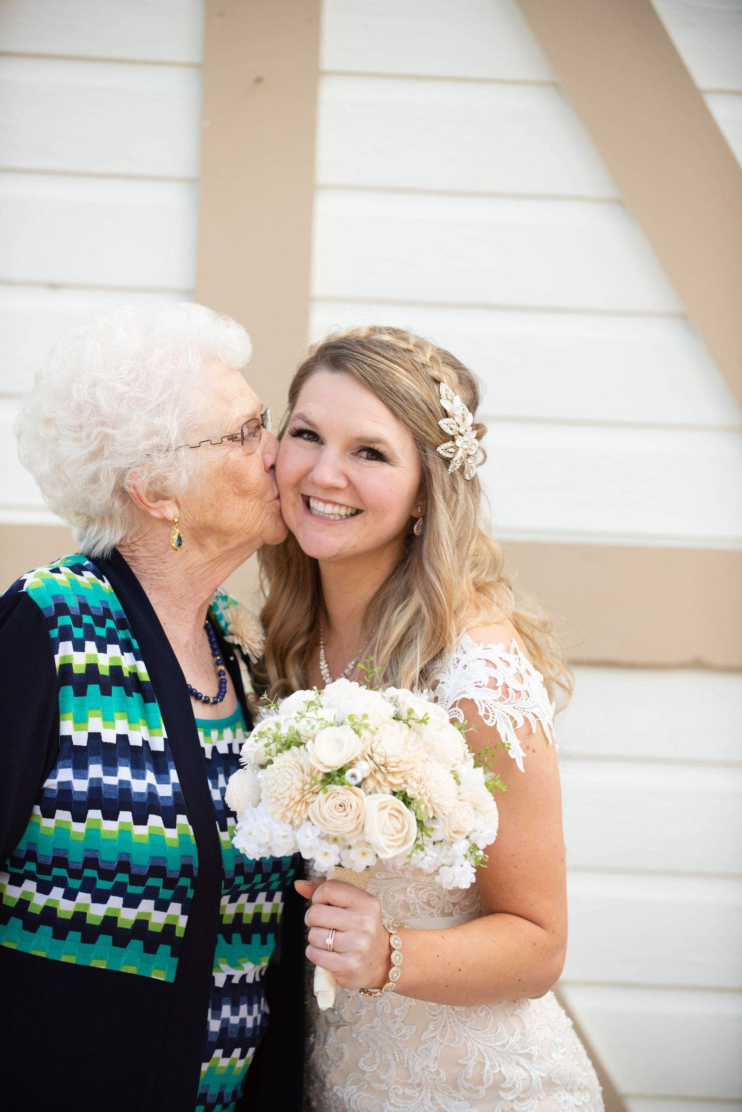 A tender wedding day moment with a bride in lace holding a white bouquet next to a family member. Milaca Minnesota Weddings