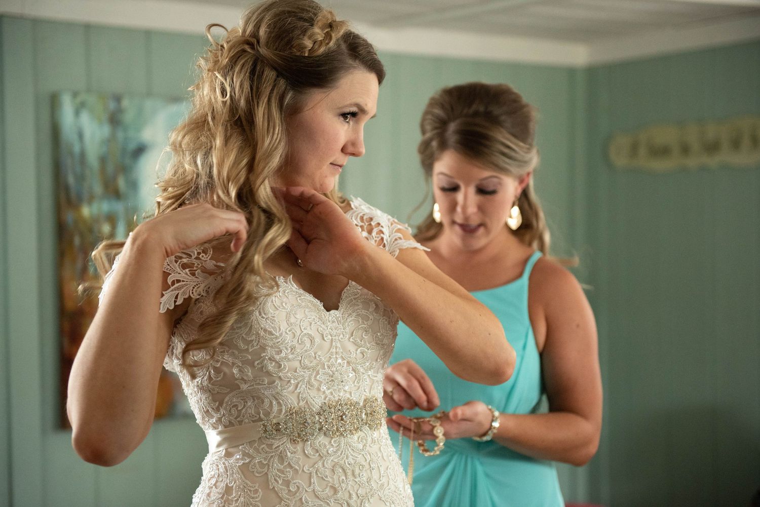 Final adjustments being made to a beautiful lace wedding dress in a mint green room. Rum River Barn Milaca Minnesota Weddings