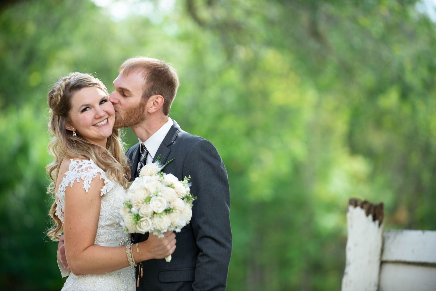 Intimate moment captured with white bouquet during outdoor wedding photoshoot. Rum River Barn Milaca Minnesota Weddings