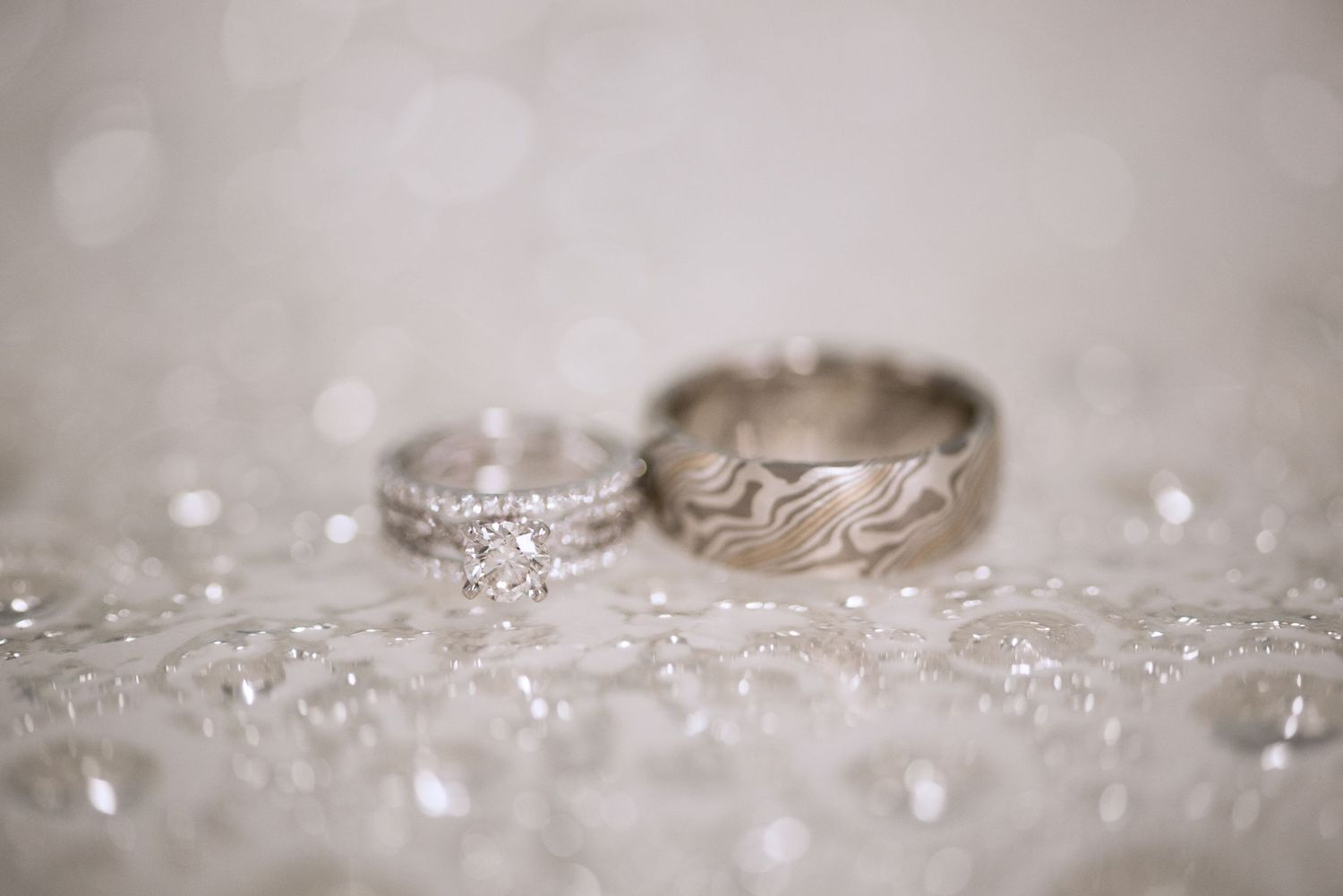 Close-up of elegant wedding rings with sparkling diamond details on textured surface. Andover wedding at Magestic Oaks Golf Club