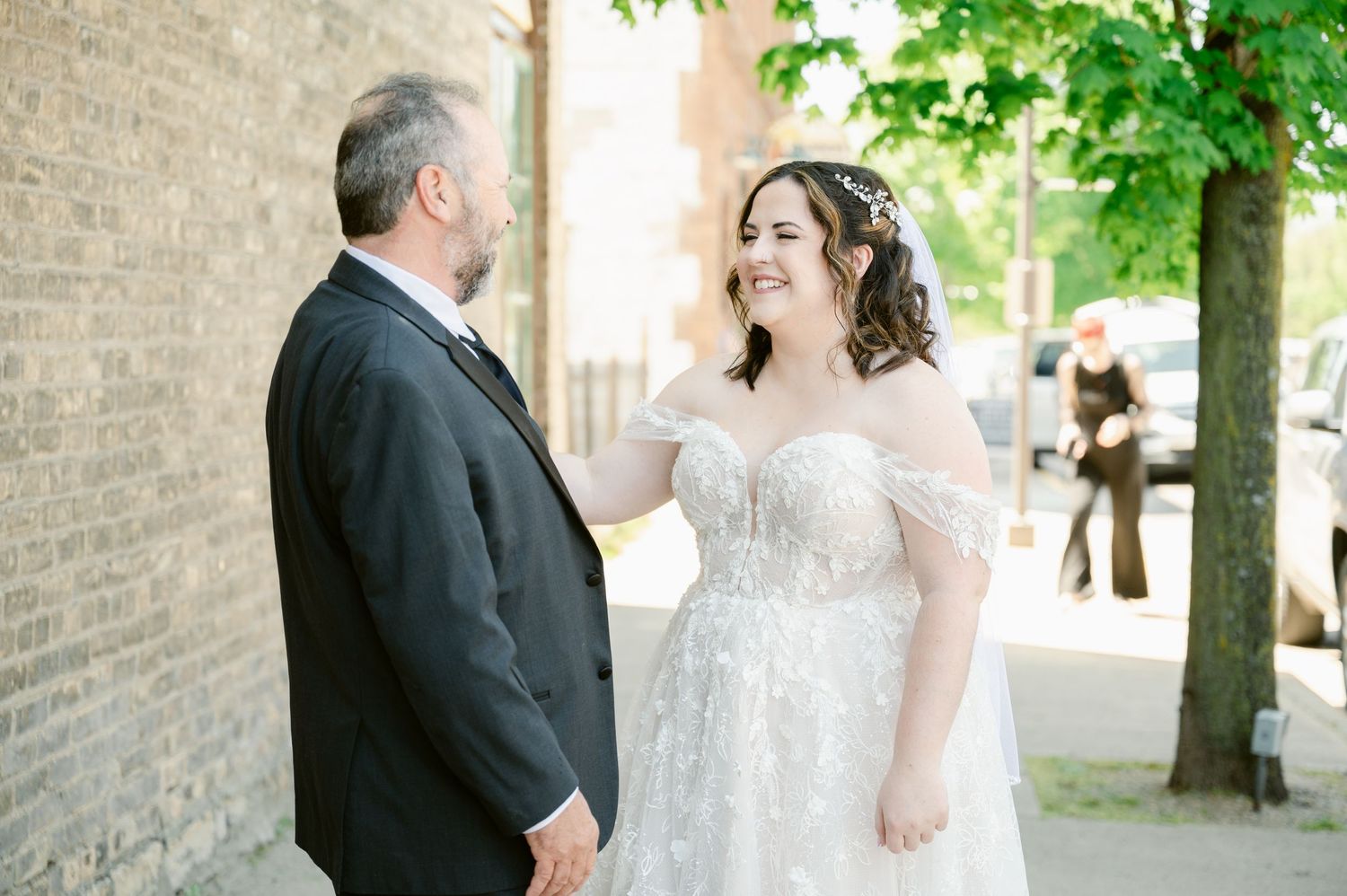 A tender moment shared between two people at an outdoor wedding next to a brick wall.
